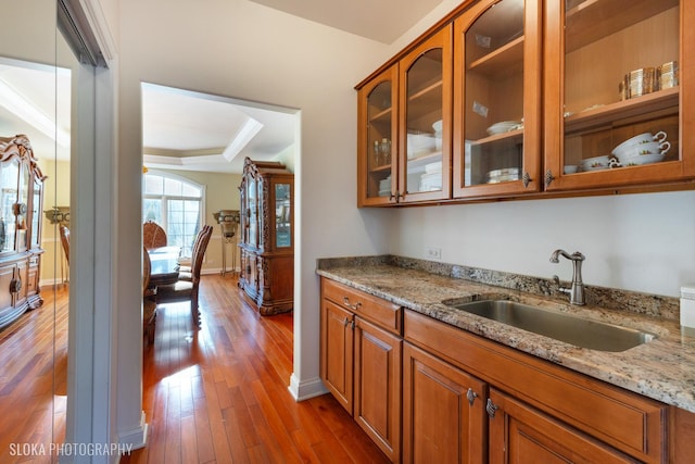 kitchen featuring sink, crown molding, light stone counters, a tray ceiling, and dark hardwood / wood-style flooring