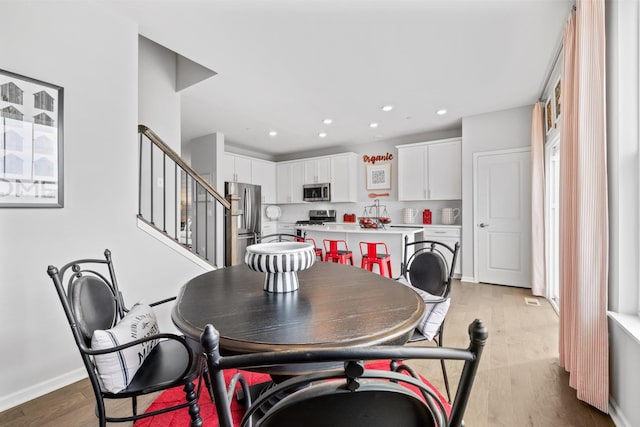 dining area featuring light wood-style floors, stairway, baseboards, and recessed lighting