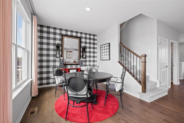 dining area featuring dark wood-type flooring, stairway, visible vents, and wallpapered walls