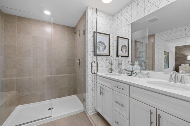 bathroom with a shower with door, tile walls, and vanity