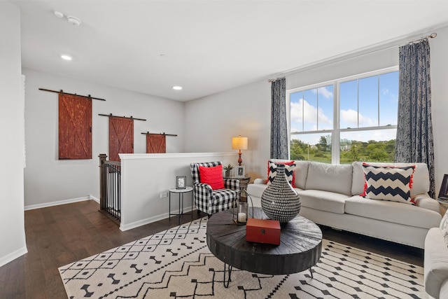 living area featuring a barn door, baseboards, dark wood finished floors, and recessed lighting