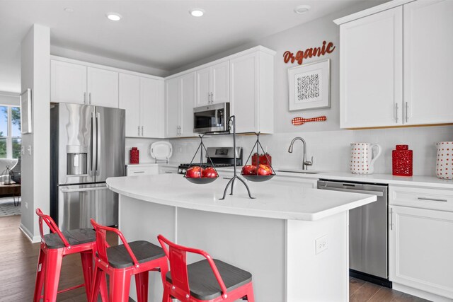 kitchen featuring dark hardwood / wood-style flooring, a breakfast bar area, a kitchen island, sink, and stainless steel appliances