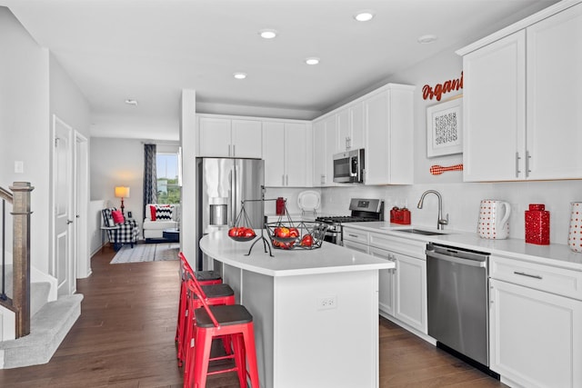 kitchen featuring white cabinets, appliances with stainless steel finishes, a center island, light countertops, and a sink