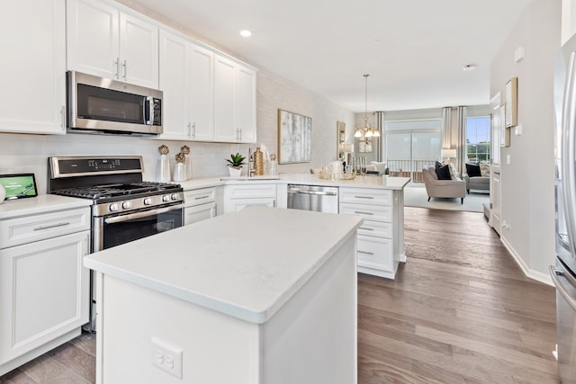 kitchen featuring kitchen peninsula, hanging light fixtures, light hardwood / wood-style floors, stainless steel appliances, and white cabinets