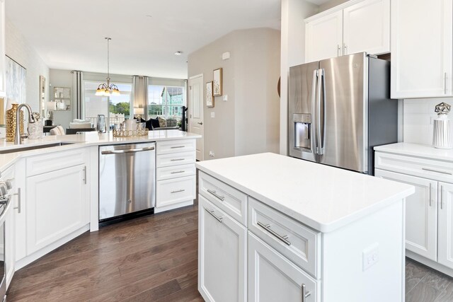 kitchen with dark hardwood / wood-style floors, sink, decorative light fixtures, white cabinetry, and appliances with stainless steel finishes