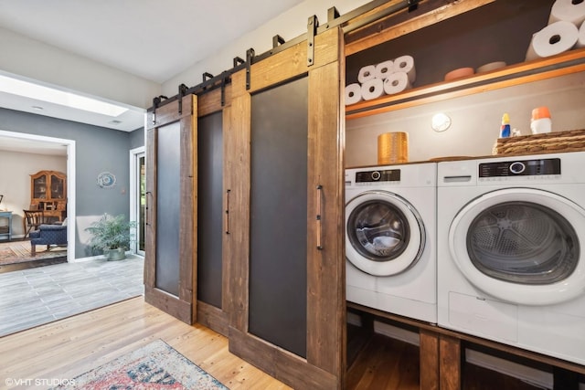 laundry area featuring a barn door, washer and dryer, and light wood-type flooring