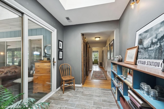 hall featuring a skylight and light hardwood / wood-style flooring