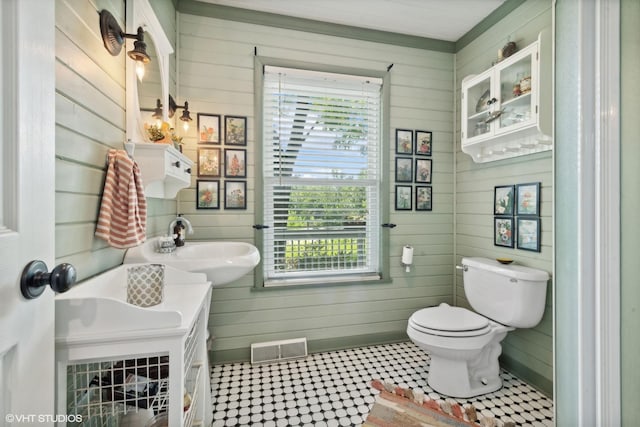 bathroom featuring wooden walls, toilet, and sink