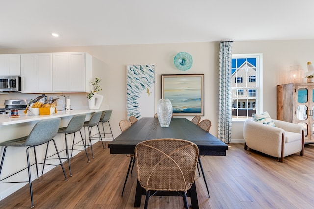 dining area with light hardwood / wood-style flooring and sink