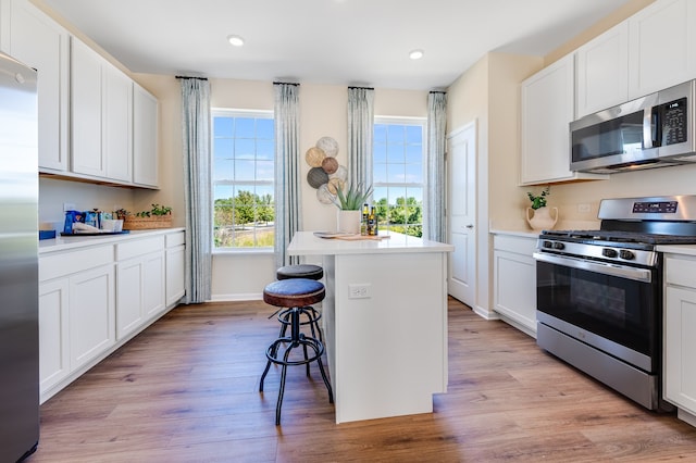 kitchen featuring appliances with stainless steel finishes, light wood-type flooring, a center island, and white cabinets