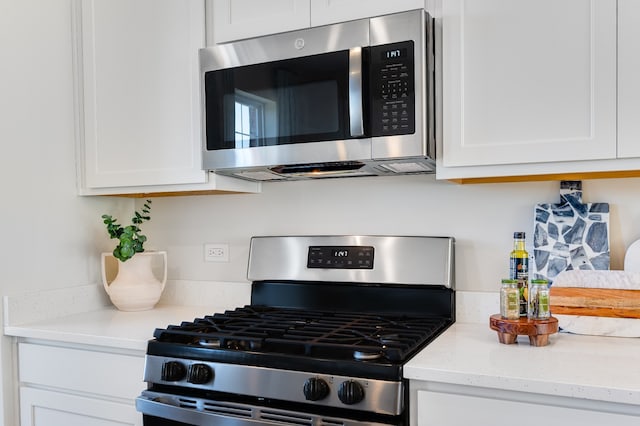 kitchen featuring appliances with stainless steel finishes, light stone counters, and white cabinets