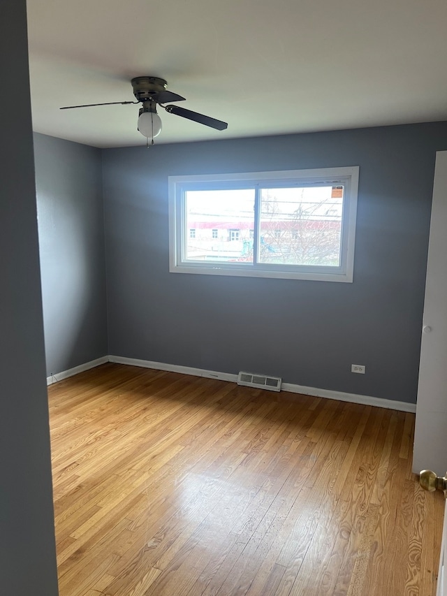 empty room with ceiling fan, a wealth of natural light, and light hardwood / wood-style flooring