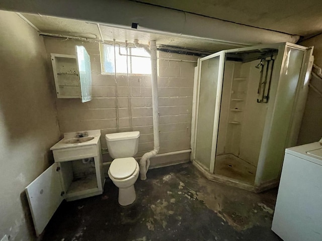 bathroom featuring toilet, an enclosed shower, concrete flooring, and washer / dryer