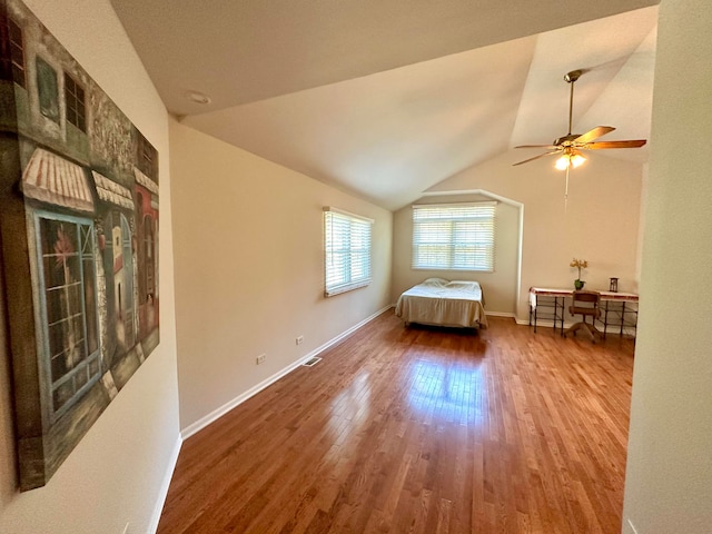 living room with ceiling fan, vaulted ceiling, and wood-type flooring