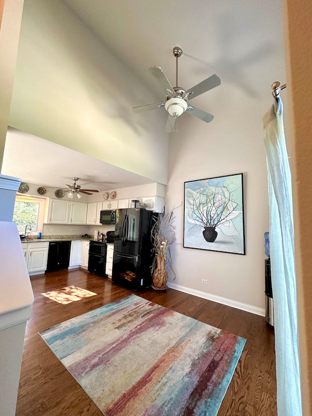 interior space featuring ceiling fan, sink, dark wood-type flooring, and a high ceiling