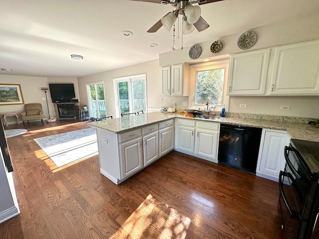 kitchen featuring a wealth of natural light, black appliances, kitchen peninsula, and white cabinets