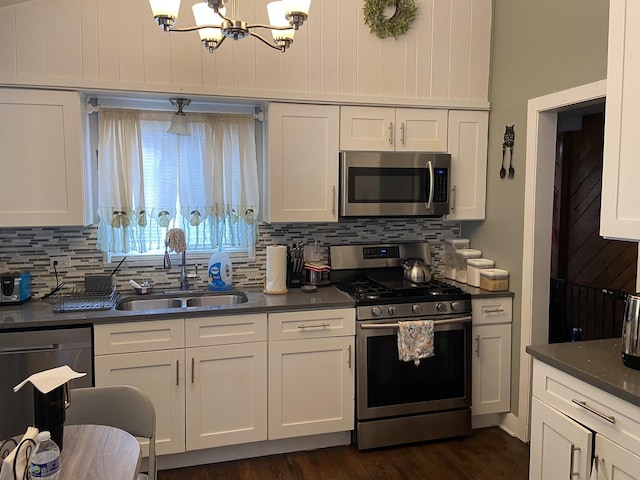 kitchen featuring stainless steel appliances, a notable chandelier, sink, white cabinets, and decorative backsplash