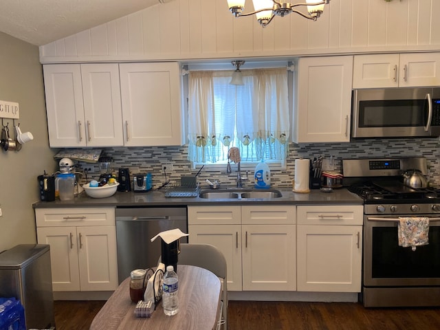 kitchen with sink, appliances with stainless steel finishes, vaulted ceiling, and dark hardwood / wood-style floors