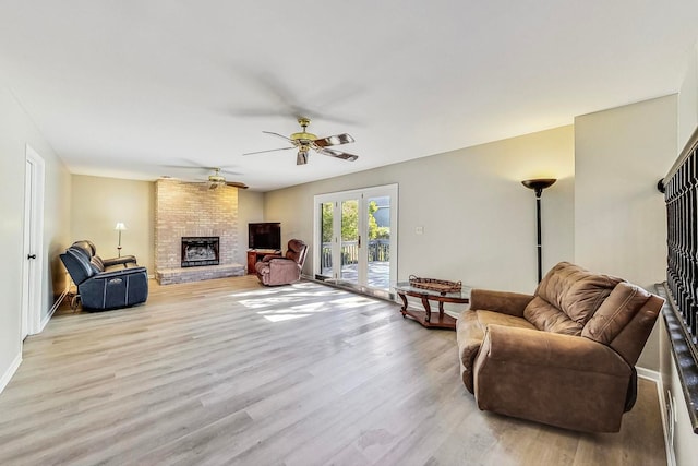 living room featuring ceiling fan, light wood-type flooring, and a fireplace