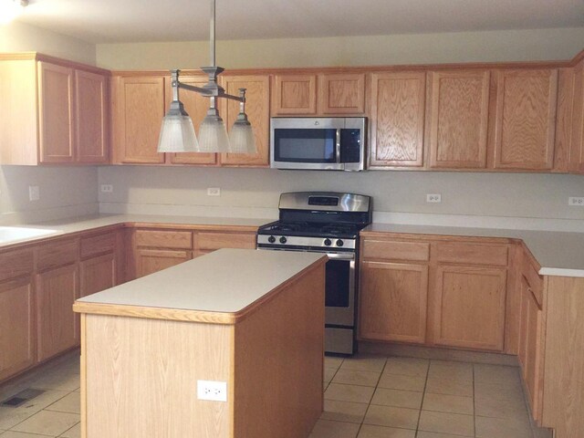 kitchen featuring pendant lighting, a kitchen island, appliances with stainless steel finishes, and light tile patterned floors