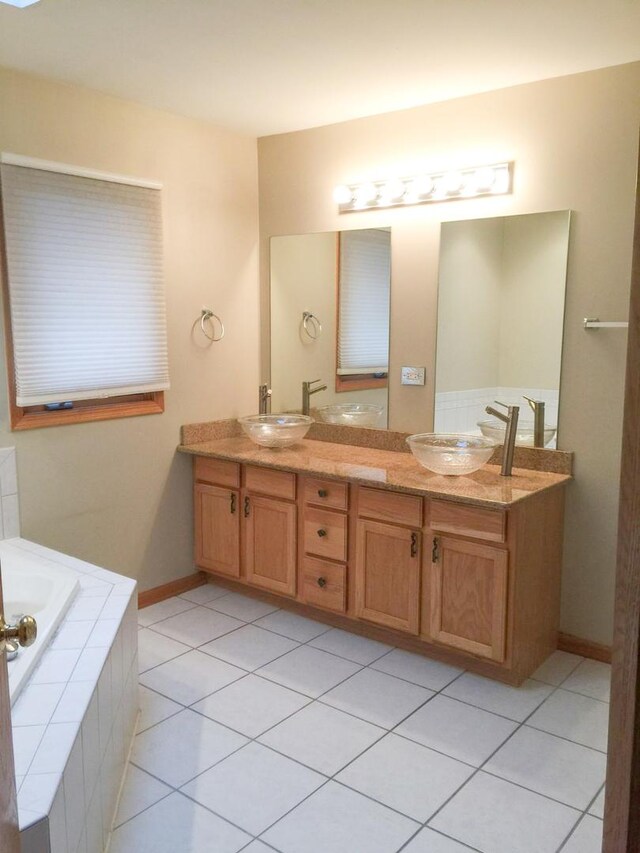 bathroom featuring tiled bath, tile patterned flooring, and dual bowl vanity