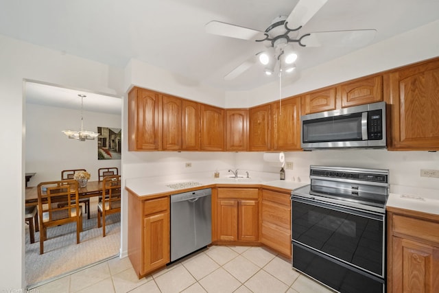 kitchen featuring light tile patterned flooring, sink, hanging light fixtures, appliances with stainless steel finishes, and ceiling fan with notable chandelier