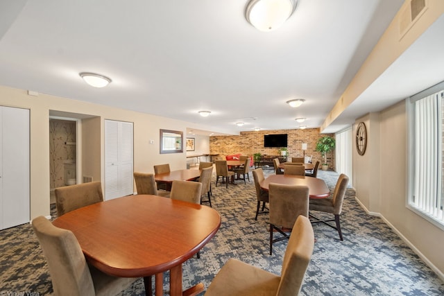 carpeted dining space with brick wall