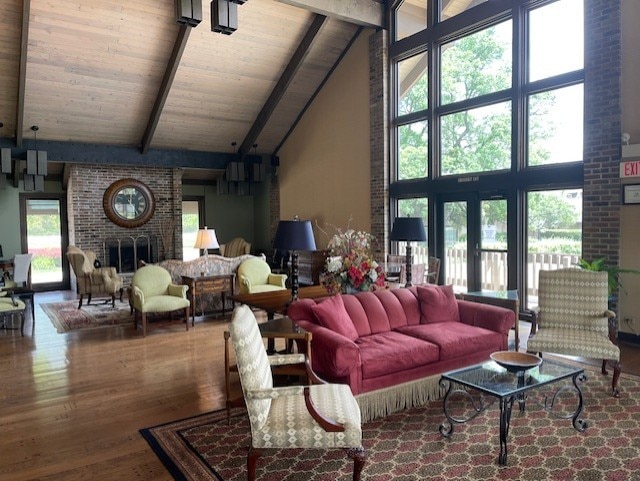 living room with beamed ceiling, a brick fireplace, hardwood / wood-style flooring, and high vaulted ceiling