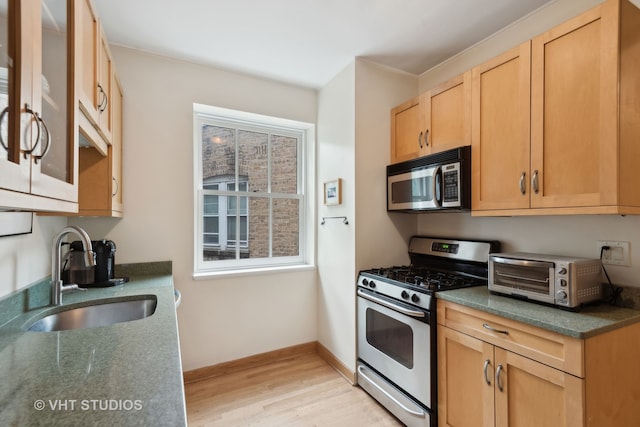 kitchen with sink, appliances with stainless steel finishes, light wood-type flooring, and plenty of natural light