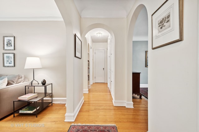 hallway featuring light wood-type flooring and ornamental molding