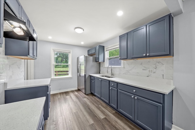 kitchen featuring hardwood / wood-style floors, sink, stainless steel fridge, and backsplash