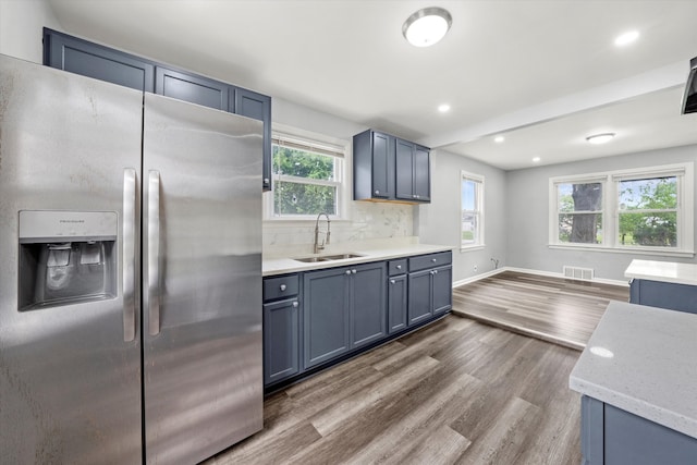 kitchen featuring stainless steel fridge, sink, decorative backsplash, and hardwood / wood-style floors