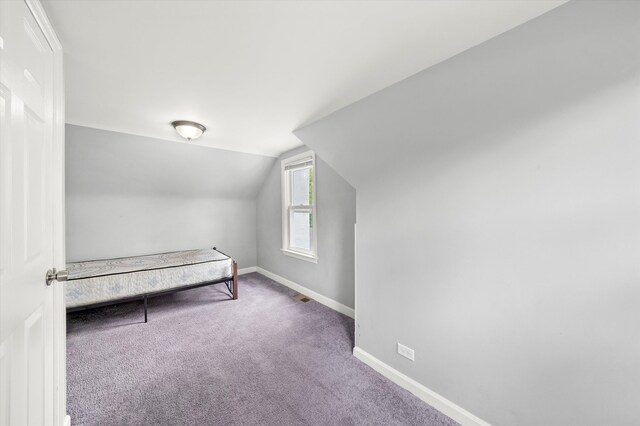 unfurnished bedroom featuring vaulted ceiling and carpet