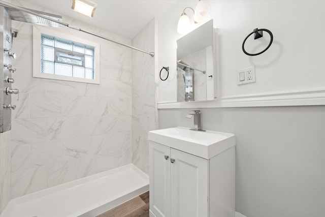 bathroom with tiled shower and vanity