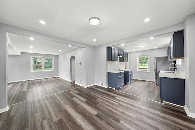 unfurnished living room featuring sink, dark hardwood / wood-style floors, and a wealth of natural light