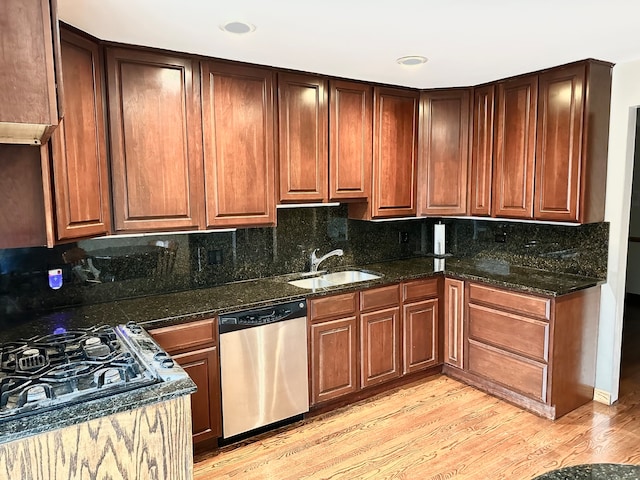 kitchen featuring dark stone counters, tasteful backsplash, sink, dishwasher, and light hardwood / wood-style flooring