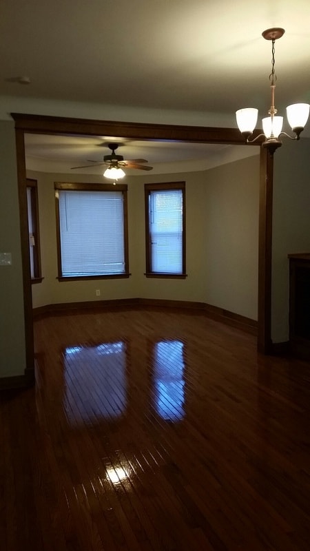 spare room featuring dark hardwood / wood-style floors and ceiling fan with notable chandelier