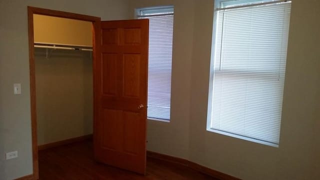 unfurnished bedroom featuring baseboards, a closet, and wood finished floors