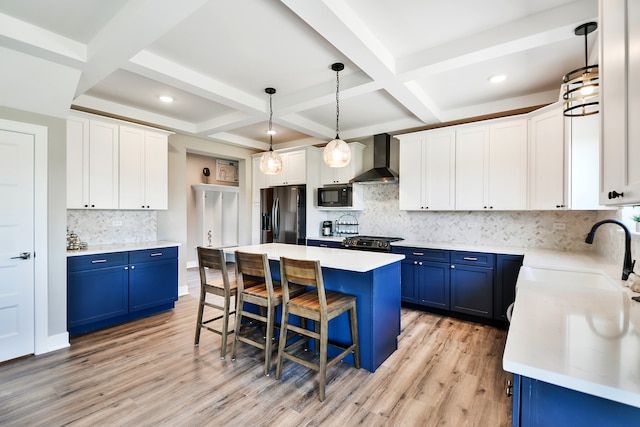 kitchen featuring wall chimney range hood, light wood-type flooring, stainless steel fridge, and coffered ceiling