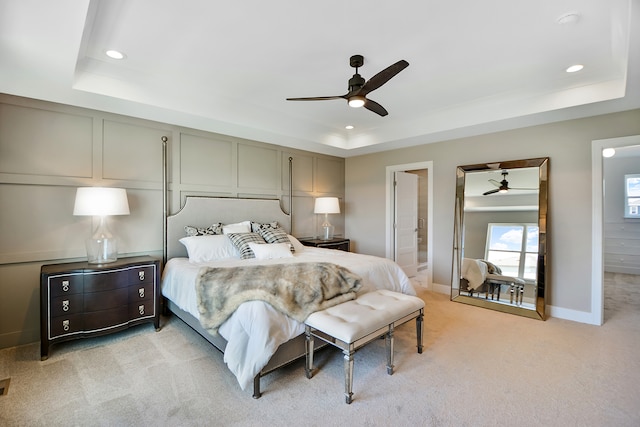 carpeted bedroom featuring ensuite bath, ceiling fan, and a raised ceiling