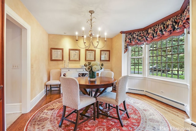 dining room with baseboard heating, light hardwood / wood-style flooring, and an inviting chandelier