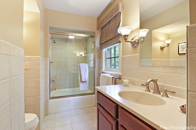 full bathroom with toilet, tile walls, tile patterned flooring, enclosed tub / shower combo, and vanity