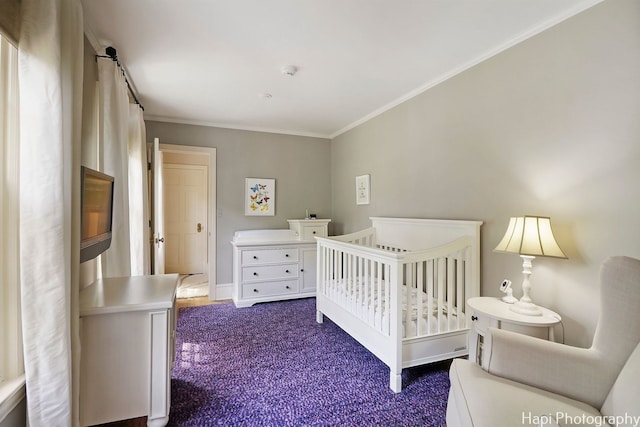 carpeted bedroom with ornamental molding and a nursery area