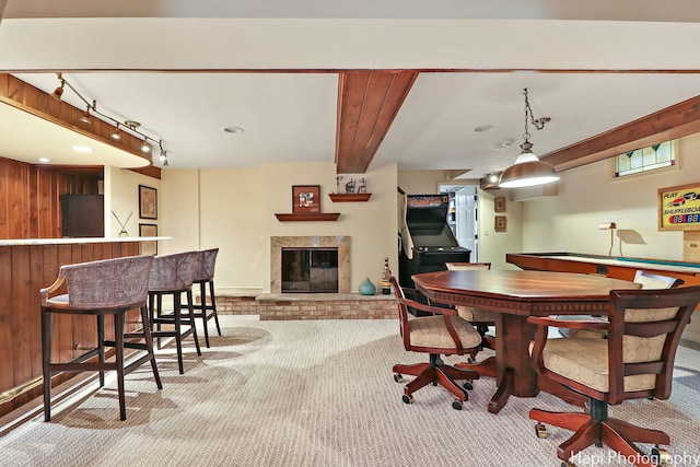 dining room with a fireplace, wooden walls, light carpet, and rail lighting