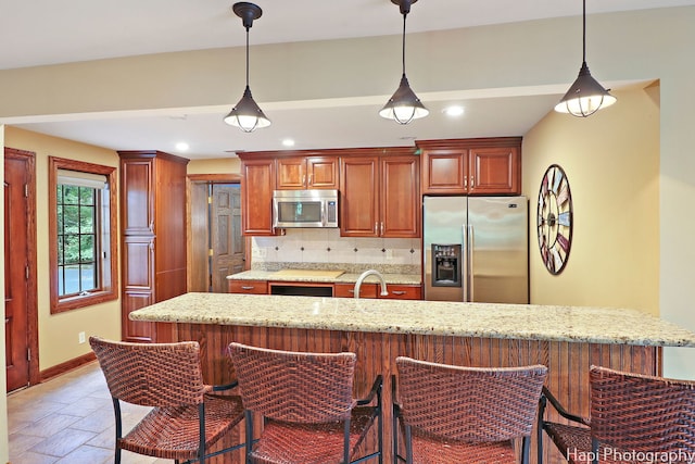 kitchen featuring a breakfast bar area, backsplash, stainless steel appliances, and hanging light fixtures