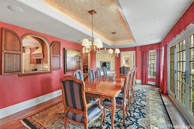 dining room with crown molding, dark hardwood / wood-style floors, a chandelier, and a tray ceiling