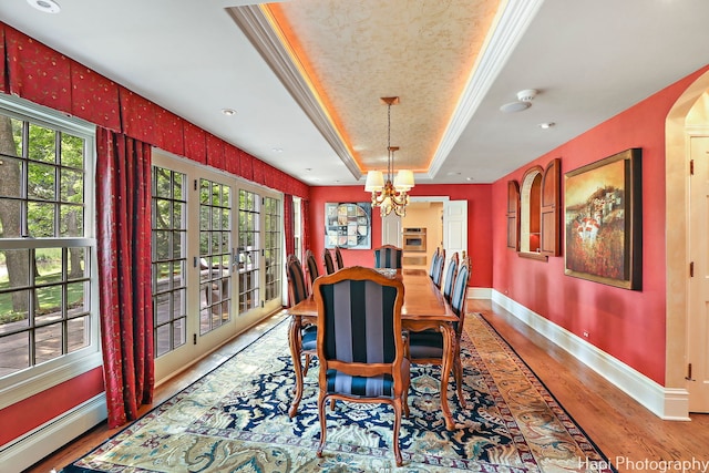 dining area featuring ornamental molding, an inviting chandelier, baseboard heating, light wood-type flooring, and a tray ceiling