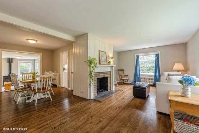 living room featuring dark hardwood / wood-style flooring, a brick fireplace, and radiator