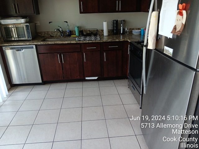 kitchen with light tile patterned floors, dark stone countertops, appliances with stainless steel finishes, and sink