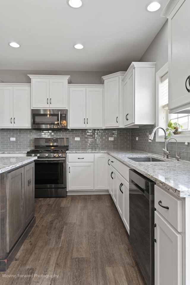 kitchen featuring appliances with stainless steel finishes, sink, white cabinets, and light stone counters